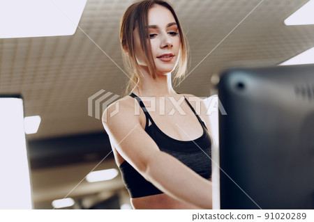 Pretty fit woman in black sportrswear training on a treadmill Pretty fit woman in black sportrswear training on a treadmill 91020289