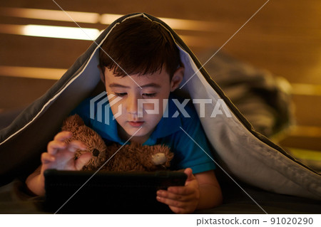 Boy Playing Game on Tablet at Night Boy Playing Game on Tablet at Night 91020290