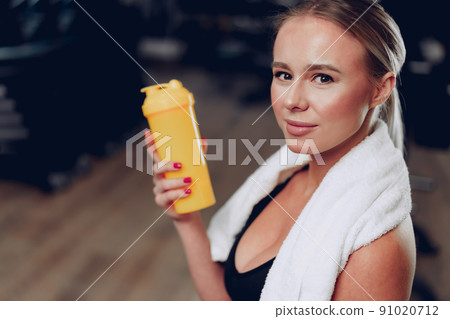 Young sporty woman having a drink in a gym after workout 91020712