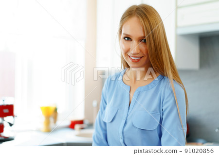 Blonde woman standing in kitchen and cooking 91020856