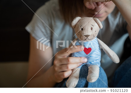 Perinatal loss reproductive chalenge concept - female holding a teddy bear toy Perinatal loss reproductive chalenge concept - female holding a teddy bear toy 91021120