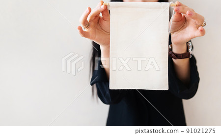 Young business woman in a black suit shows a blank white billboard on a white isolated background. Place for the inscription on the poster. Young business woman in a black suit shows a blank white billboard on a white isolated background. Place for the inscription on the poster. 91021275