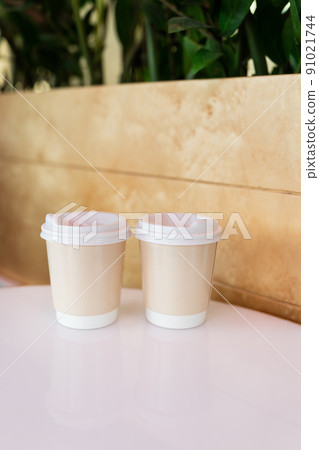 Two paper coffee cups in a cafe, coffee to go concept. Walks in the open air. Two paper coffee cups in a cafe, coffee to go concept. Walks in the open air. 91021744