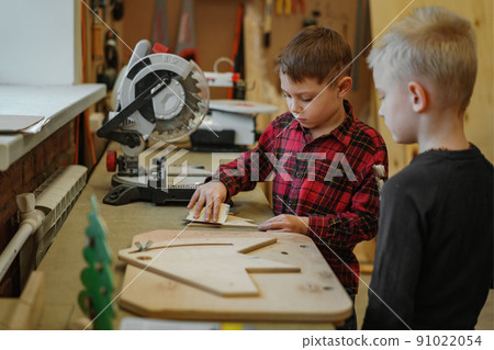 cute caucasian preschooler boys msking a wooden christmas tree in joinery class. 91022054