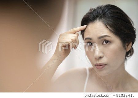 Arafif woman who cares about her hairline while looking in the mirror 91022413