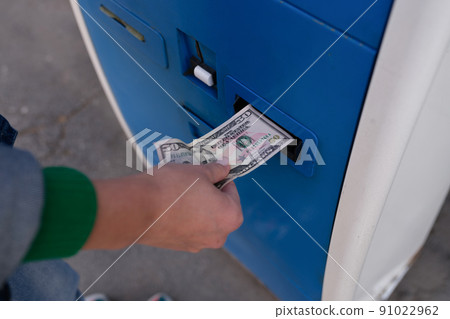 Woman paying for parking using cash at teller machine. 91022962