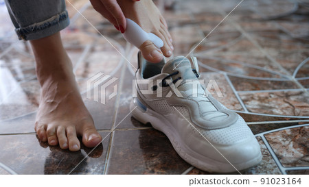 Woman using brace for hallux valgus and putting on sneaker Woman using brace for hallux valgus and putting on sneaker 91023164