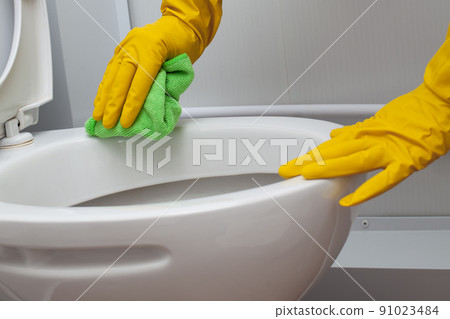 Hands in yellow gloves cleaning a WC 91023484