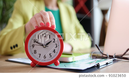 Businesswoman putting alarm clock on table, time management and deadline Businesswoman putting alarm clock on table, time management and deadline 91023650