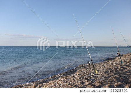 Fishing rods on sea beach, seaside landscape Fishing rods on sea beach, seaside landscape 91023891