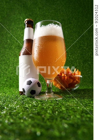 Bottle and glass of beer on the green grass background. 91024312