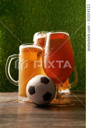Four glasses of beer with soccer ball on the green grass background. Four glasses of beer with soccer ball on the green grass background. 91024313