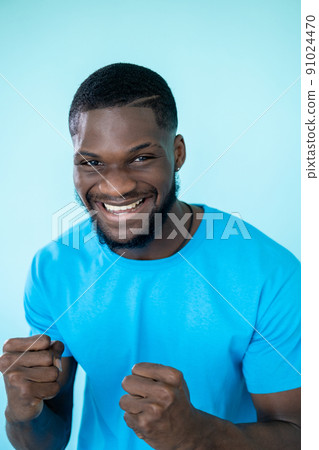 Man winner. Achievement success. Victory joy. Happy celebrating excited smiling guy clenches fists in triumph on blue background. Man winner. Achievement success. Victory joy. Happy celebrating excited smiling guy clenches fists in triumph on blue background. 91024470