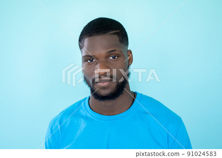 Man face. Studio portrait. Neutral expression. Headshot of handsome young beardy calm emotion guy isolated on light blue free space background. 91024583