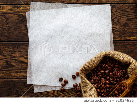 Coffee beans in sack, white paper copy space over wooden background 91024656