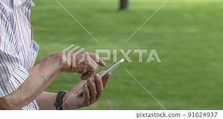 Elderly man using a smartphone in the park 91024937