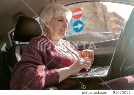 Joyous senior woman seated in the automobile Joyous senior woman seated in the automobile 91025091