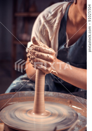 Potter master woman creates a new pottery from clay on a potter's wheel. Handicraft. Close-up. 91025504