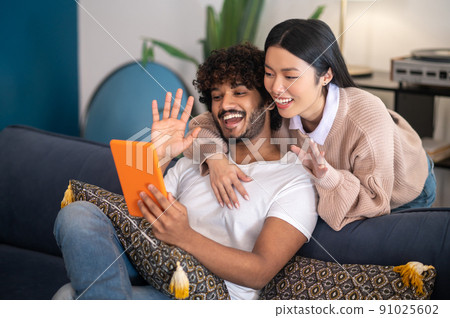 Young cute couple having a video call and looking involved 91025602