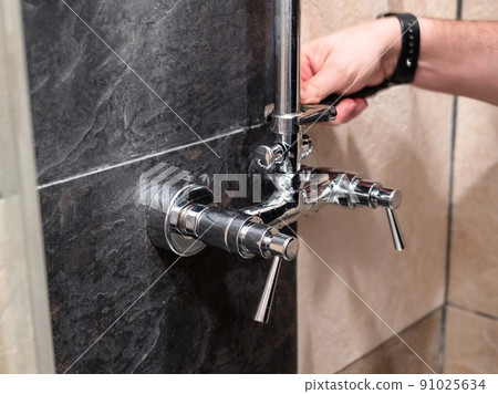 plumber fixes shower pipe to faucet valve at home 91025634