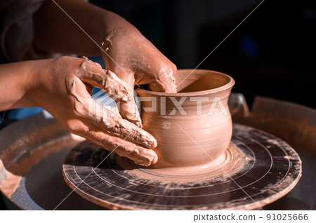 Potter master woman sculptor works with clay on a Potter's wheel and at the table with the tools. Close-up. Potter master woman sculptor works with clay on a Potter's wheel and at the table with the tools. Close-up. 91025666