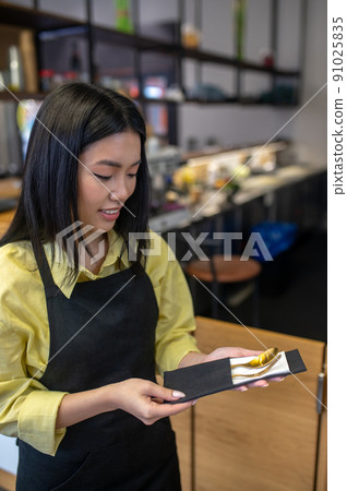 Woman holding looking at cutlery packed in napkin 91025835