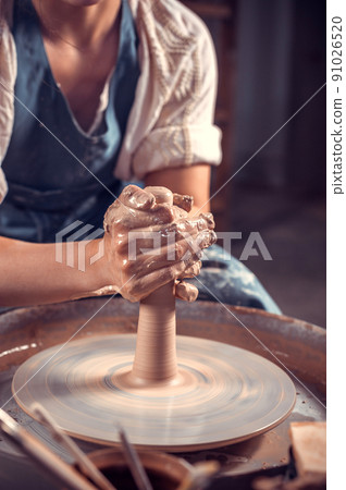 Creating vase of white clay close-up. The sculptor in the workshop makes a jug out of earthenware closeup. Twisted potter's wheel. Master crock. 91026520