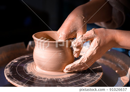 Craftsman's hands and potter's wheel. Close-up. Craftsman's hands and potter's wheel. Close-up. 91026637