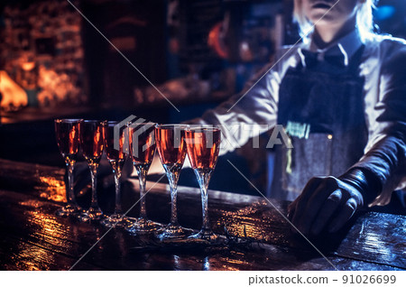 Sweet girl tapster decorates colorful concoction behind the bar 91026699