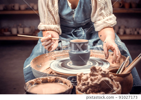 Pottery girl is working on pottery wheel. Folk handicraft. Close-up. Pottery girl is working on pottery wheel. Folk handicraft. Close-up. 91027173