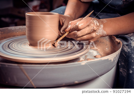 Close-up of potter's hands with the product on a potter's wheel 91027194