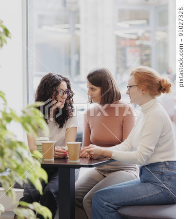 three female colleagues or students are working on a laptop and discussing a project or creative term paper. three female friends in coworking work online in an intranet three female colleagues or students are working on a laptop and discussing a project or creative term paper. three female friends in coworking work online in an intranet 91027328