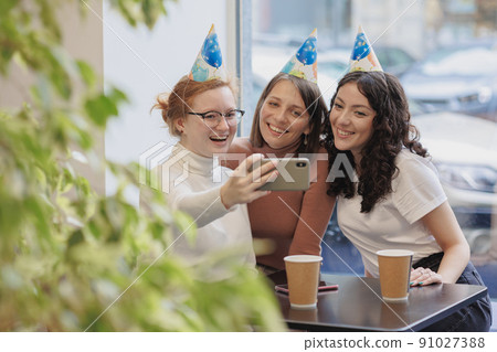 friendship and support, three women celebrate their birthday in a coffee shop, restaurant and call friends via video chat friendship and support, three women celebrate their birthday in a coffee shop, restaurant and call friends via video chat 91027388