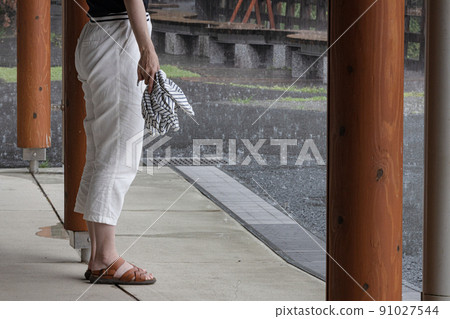 A woman sheltering from the rain A woman evacuating under the roof 91027544