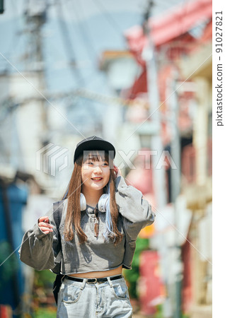 Z 世代女性脖子上戴著耳機走路 91027821