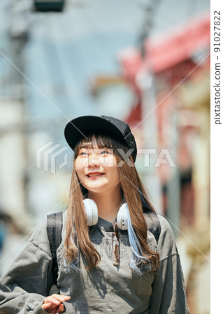 Gen Z woman walking with headphones around her neck 91027822