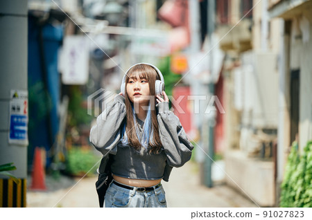 Gen Z women listening to music on headphones 91027823