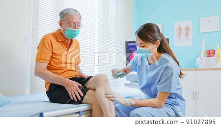 doctor examining patient knee 91027895