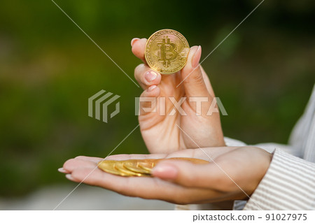 Closeup of hand holding golden bitcoin, copy space for cryptocurrency commercial, digital money, electronic investment. Cropped portrait of businesswoman holding bitcoin and showing it to the camera. 91027975