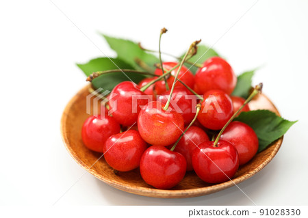 Cherry on a wooden plate with leaves on a white background 91028330