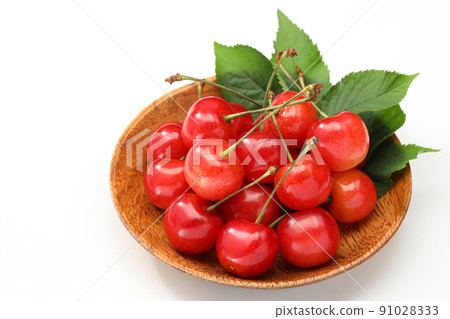 Cherry on a wooden plate with leaves on a white background 91028333