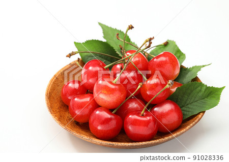 Cherry on a wooden plate with leaves on a white background 91028336
