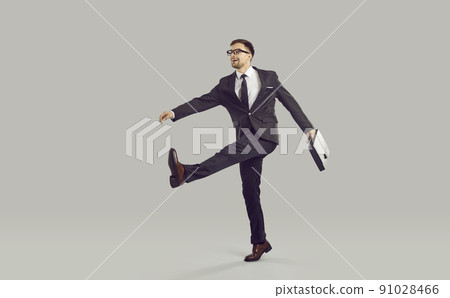 Businessman with briefcase and crazy expression ridiculously goes to work in company's office. Businessman with briefcase and crazy expression ridiculously goes to work in company's office. 91028466