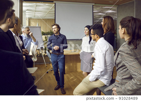 Variety of multiracial smart employees communicate at team meeting in modern office. 91028489