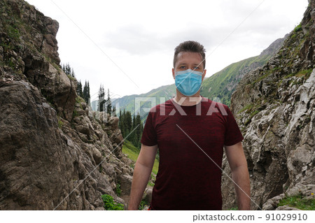 Guy in the mountains takes off his medical mask. 91029910