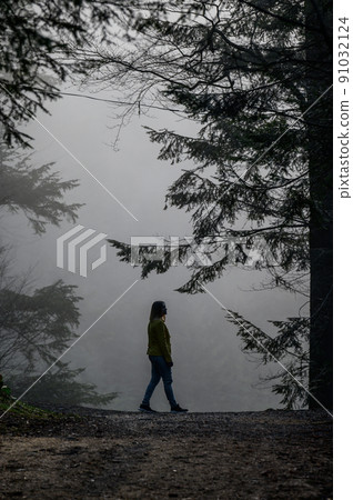A woman like a ghost walks through the misty forest, the fear and mystery of the fog in the woods. 91032124