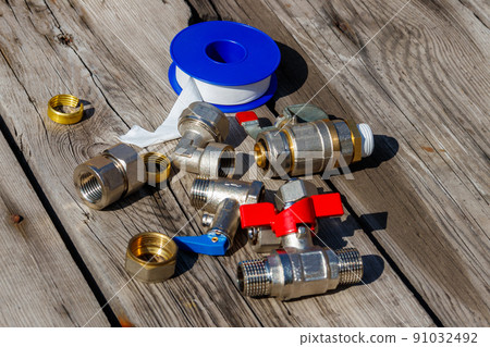 Various plumbing spare parts and sealing tape on rustic wooden background Various plumbing spare parts and sealing tape on rustic wooden background 91032492