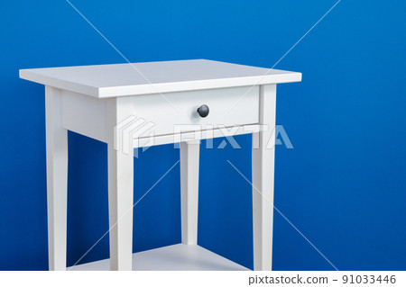 White wooden nightstand table against blue wall 91033446