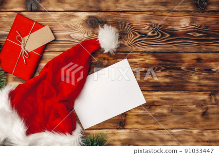 Santa Claus cap and Christmas gift on wooden background top view Santa Claus cap and Christmas gift on wooden background top view 91033447