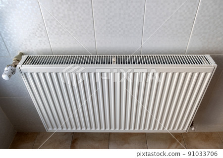 White metal heating radiator mounted on a wall in room interior. 91033706